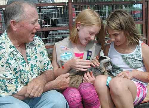 Mayor Jimmie-John King, left, introduces a baby goat from his rural Stewartville farm to Madigan Lawrence, 11, of Stewartville, center, and Aryana Baerthel, 10, also of Stewartville, at the Stewartville Area Chamber of Commerce's Tuesdays off Main event at the downtown city parking lot on Tuesday, June 9. Working in 90-degree heat, a number of local and area residents sold items from booths at the Farmers Market that day.