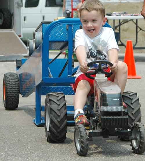 Justin Byrne, 4, of Stewartville, smiles at his cheering family as he increases his distance in the 4-year-old class at the Kids Power Pedal Tractor Pull.