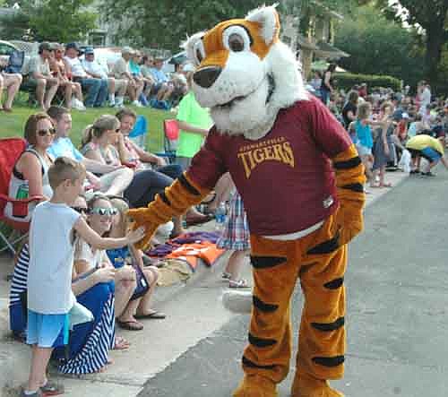 The Stewartville Tiger offers a paw to a young fan standing along the curb during the Fourth of July Summerfest Parade.