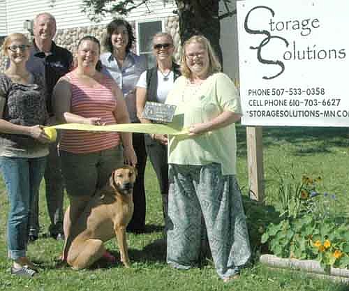 Members of the Stewartville Area Chamber of Commerce welcomed Storage Solutions to the Chamber with an official ambassador visit on Wednesday, July 29. Jennifer Martin, the owner of Storage Solutions, joined by her dog, Jack, cuts the ribbon celebrating the official opening of her business and accepts a Chamber plaque from Gwen Ravenhorst, Chamber administrator, standing in front at right, and Melissa Sue Leuning, standing in front at left. Other Chamber members who welcomed Martin include, in back, from left, Bill Schimmel Jr., city administrator; Margaret Nelson and Beth Schmidt. The business has 22 storage units, the larger of which are 10 feet by 15 feet and the smaller of which are five feet by 10 feet. The business also offers storage for boats and vehicles on a first-come, first-served basis.