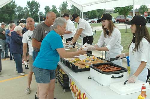 Hundreds of Stewartville and area residents ate free hot dogs and sampled a number of free side items provided by seven northeast Stewartville businesses at the third annual Dog Days of Summer celebration on Thursday, Aug. 6. Above, Fareway employees serve hot dogs to guests who stood in a long line in the Fareway parking lot.