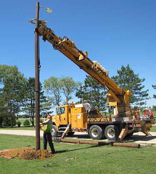  Brian Ideker of People's Energy Cooperative sets a light pole in place at Bear Cave Park on Wednesday, July 29. The city of Stewartville is increasing security lighting at the park, which is expected to be used as a route to the city's new school. The city purchased the poles and lights from People's Energy Cooperative, which donated the cost of setting the poles.