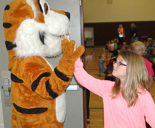 Avery Spencer, a fifth grader at Central Intermediate School, gives the Stewartville Tiger a high five after an all-school assembly in the school's gym on Monday, Aug. 24. 