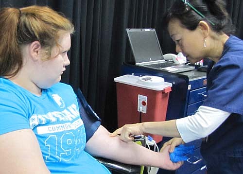 Samantha Bush, a senior at Stewartville High School, gives blood at the Mayo Clinic Blood Drive at SHS on Tuesday, Sept. 1. Nghia Le, a blood donor lab tech for the Mayo Clinic, prepares Samantha for the  donation.