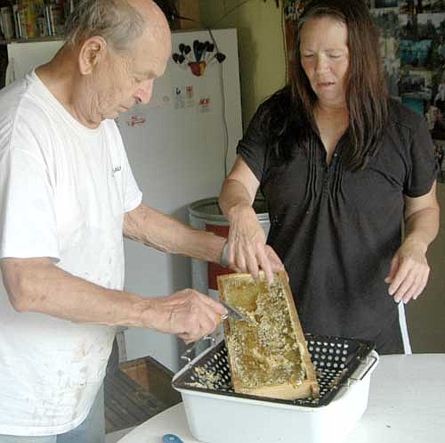 Buck and his daughter, Gina, clean the beeswax off a frame before placing the frame inside the  extractor.
