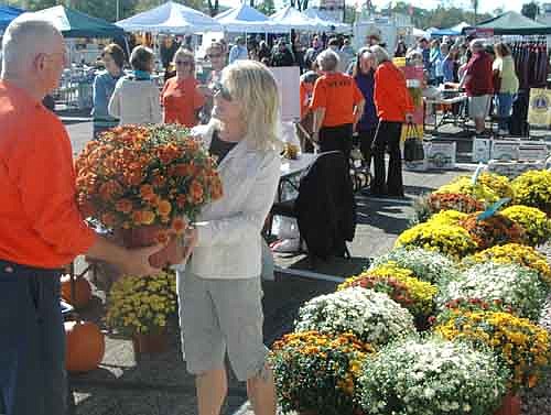 Krys Zahradnik of Stewartville and Clair Mrotek of the Stewartville Morning Lions Club, at left in the foreground, look over the mums at the annual Morning Lions Fall Festival at the Strikers Corner and Stewartville American Legion Post 164 parking lots on a cool and sunny Saturday morning, Sept. 19. Hundreds of local and area residents attended the event.