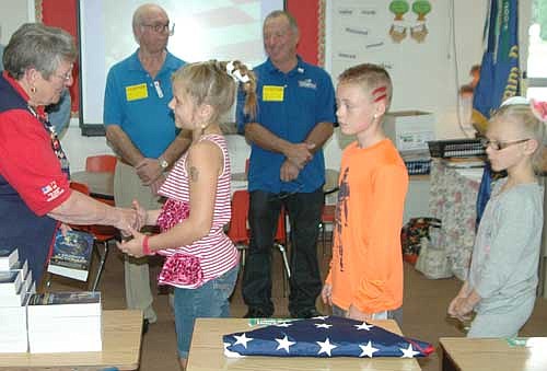 Kay Tvedt of the Stewartville Morning Lions Club, far left, handed out dictionaries to third graders at Bonner Elementary School, above, and at Central Intermediate School on Thursday, Sept. 24. Members of the Stewartville American Legion Post 164 and the Prescher-Kumm VFW&#8200;Post 8980 also took part in the ceremony, which included a demonstration of the proper way to fold an American flag. Standing in the background are Ron Piedmont of the Morning Lions, left, and Mayor Jimmie-John King, who praised American servicemen and women for their efforts to keep America free.