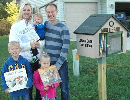 C.J. and Carrie Boerger, 611 Twelfth Avenue Ave. Southeast, Stewartville, welcome local and area residents to check out the books for children and adults in the already-popular mini library at a corner of their front lawn.  The Boergers' children include, front row, from left, Charlie, 7; and Chloe, 4. Caleb, 17 months, is sitting in Carrie's arms.