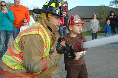 Bryson Link, 4, of Stewartville, operates a fire hose with assistance from firefighter Brandon Berg at the Stewartville Fire Department's annual open house last Wednesday, Oct. 7.