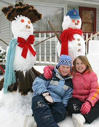 Natalie Jaeger, 8, left, and her sister Amanda, 11,  built two snowmen at the home of Darrel and Julie Jaeger last week. The girls used a number of unique items, including turkey feathers for a hat, golf balls for eyes, a red bow and  cedar wood for noses and buttons.  Grandpa Darrel Jaeger, who helped with the construction, is not pictured. 