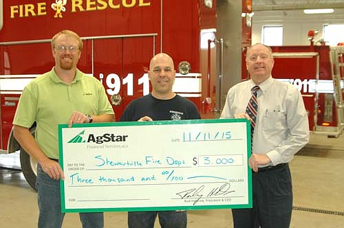 Nate Reid, financial services officer for AgStar Financial Services, left, presents a $3,000 check to Vance Swisher, Stewartville fire chief, center, and Bill Schimmel Jr., city administrator.