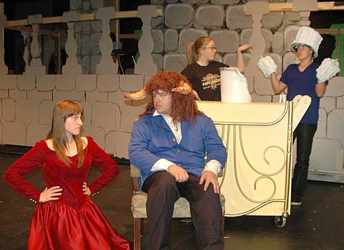 Belle (Calli McCartan), far left, and the Beast (George Skare), seated, face off in a battle of wills while Mrs. Potts (KyAnne Hilger)  and Lumiere (Brenndan Walton), in background, think this might be the girl to break the spell during a dress rehearsal for Stewartville High School's Beauty and the Beast.