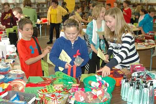 Anni Welch, at right in the foreground, smiles brightly as she and her fellow fifth graders Brody Seim, at left in the foreground, and Josie Kahoun, center, browse among the colorfully packaged items at the annual BACPAC Santa Shop at Central Intermediate School on Wednesday, Dec. 2. BACPAC organizes the Santa Shop to raise money to help students.