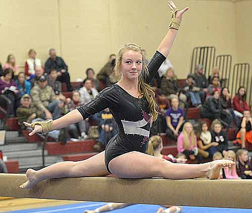 Mckenna Wheeler smiles and glances at the judges while balancing in the splits on the beam.