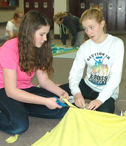 Maya Ramp, left, and Isabel Field, eighth graders, work together to cut and tie a blanket for the children at the Ronald McDonald House in Rochester.
