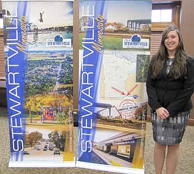 Joya Stetson of CEDA poses with the retractable banners that were on display at the Stewartville booth at the Rochester Area Builders Home Show Feb. 6-8.