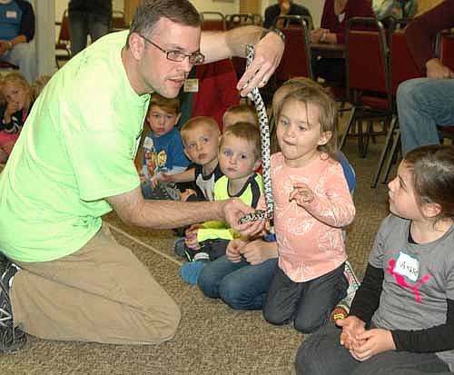 Adyson Pyfferoen, a student at St. John's Wee Care in Stewartville, center, examines a snake held by Travis Meyer, a naturalist from the Quarry Hill Nature Center, on Tuesday, Oct. 6.
