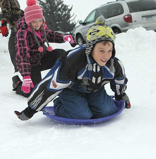 Karter Wicklund, a fourth grader, uses his arms to gain speed as he heads down the hill near Central Intermediate School. Ella Bly, another fourth grader, left, helps Karter get off to a good start.