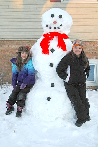 Cheryl Terhaar of Stewartville and her son Matthew made this smiling snowman at the Terhaar home at the 600 block of Fifth Avenue Southeast. They used wooden pieces for the eyes, nose, mouth and buttons. Eva Biffert, 7, left, and her sister Littia, 10, neighbors of the Terhaars, pose with the snowman.