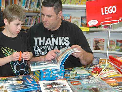 Brandon Miller of Stewartville helps his son Brett, 6, a kindergartner at Bonner Elementary School, look over the books for sale at the Central Intermediate School library during the school's third annual Hot Reads for Cold Nights Literacy Night on Friday, Jan. 29.