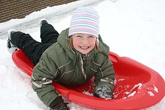 Bonner Elementary School students enjoyed jumping on their sleds and heading down the hill near the school during recess last week. Here, Abegail Van De Walker, a first-grader, smiles brightly as she prepares to take a solo ride down the hill. 