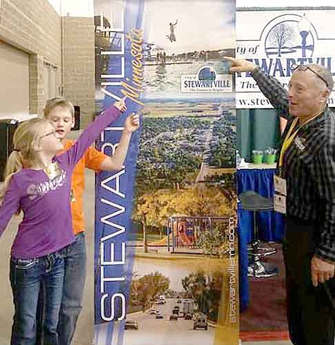 Mayor Jimmie-John King, right, served as a host at the Stewartville booth at the Rochester Area Builders Home Show, which was held Friday, Feb. 5 through Sunday, Feb. 7. At left are Katie and Jackson Struhar of Stewartville, who visited the booth.Bill Schimmel Jr., city administrator, told the City Council last week that the individuals who worked at the Stewartville booth welcomed quite a few visitors. "The numbers were good, and the inquiries were good, for commercial and residential," Schimmel said.