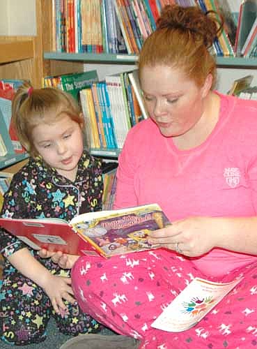 Sarah Henke of Stewartville reads Batter Up, Sponge Bob! to her daughter Lilly, 4, at the annual Pajama Party for Wee Care children and their parents at the Stewartville Public Library last Tuesday, March 8.