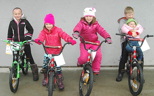 Four children won new bicycles in a drawing at the Stewartville Sons of the American Legion Easter Egg Hunt at Florence Park on Saturday, March 26. From left are Kayleigh Mourning, standing in for her brother, Kingsten Nelson, 4, of Stewartville, who won the bicycle on which Kayleigh is sitting; and the other winners, Kaia Bicknese, 6, of Stewartville; Grace Amy, 7, of Stewartville; and Ava Monty, 1 1/2, of Grand Meadow, held by her brother, Ethan Monty.