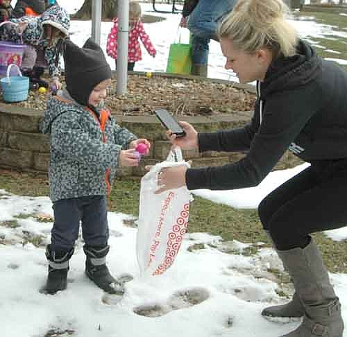 Liam Maxwell, 2, of Rosemount, Minn., deposits his Easter eggs into a plastic bag held by Jennifer Maxwell of Stewartville, Liam's aunt, at the Stewartville Sons of the American Legion Easter Egg Hunt at Florence Park on a snow-covered Saturday morning, March 26. About 80 children hunted for hundreds of eggs at the event.