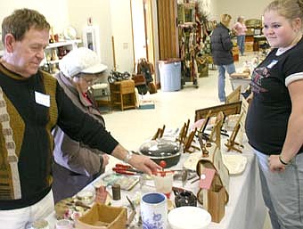 JUST BROWSING -- Hanah Distad of Wabasha, right,  offered "Original Photography" by Tamra Distad at the Stewartville Area Historical Society's 12th annual cabin fever flea market at the Stewartville Civic Center on Saturday, Feb. 16. Ron Henry of J&R Antiques & Gifts, Pine Island, left, looks over a few of the displayed items. 
