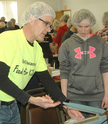 Todd Weston of the Stewartville Kiwanis Club, left, shows Sally Broadwater how to use a sealing machine at the 13th annual Food for Kidz food-packaging event at the Stewartville Civic Center on Saturday, April 9.Weston was a co-chair of the event.