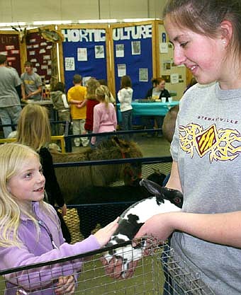 An FFA member shows a young observer a bunny rabbit at the FFA petting zoo. 