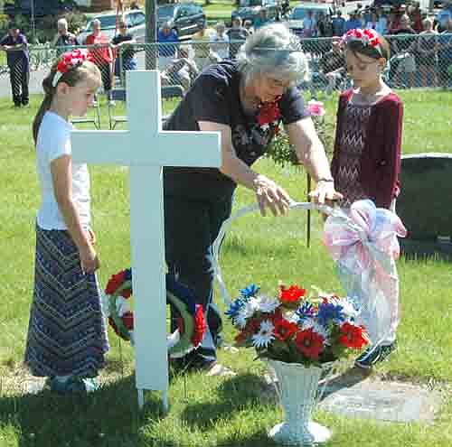 Sheila Majerus, the poppy queen for the Stewartville American Legion Auxiliary Unit 164, places a wreath at Woodlawn Cemetery as poppy princesses Aubrey Frisch, left, and Autumn Wright look on.