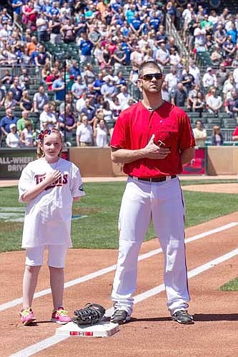 Emma Mestad of Stewartville,  left, faces the flag and stands with  Joe Mauer at first base before the Twins played the Toronto Blue Jays on May 22.