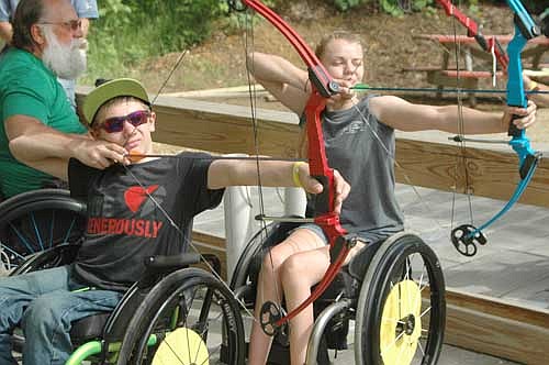 Campers Jace Hanson of Fosston, Minn., left, and Brynn Duncan of Moorhead, Minn., zero in on the target during archery practice at the National Wheelchair Sports Camp at Ironwood Springs Christian Ranch last Wednesday, June 15. Ron Malik, archery instructor from Tremont, Ill., is at far left.