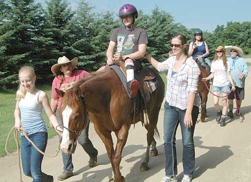 Wyatt Johnson of St. Paul, wearing the purple helmet, and Heather McClay of Rochester, in the background, ride horses at the National Wheelchair Sports Camp at Ironwood Springs Christian Ranch last Wednesday, June 15.