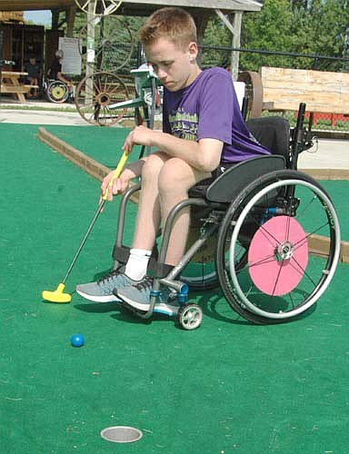Noah Hanson of Rochester watches the ball roll toward the hole as he putts during his round of mini-golf at Ironwood Springs Christian Ranch's 30th annual National Wheelchair Sports Camp last Wednesday, June 15.