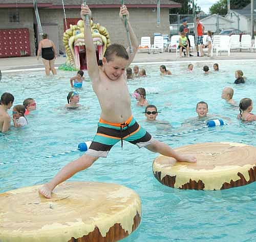Tommy Lofgren, 7, of Stewartville, who will be a second grader at Bonner Elementary School this fall, grasps the ropes tightly as he struggles to cross the imitation logs at the Stewartville pool on Tuesday afternoon, June 28. Hundreds of children had fun at the pool that day under partly cloudy skies with temperatures in the mid-70s.