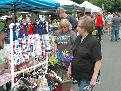 Sharon Theobald of Stewartville, at right in foreground, and Carol and Steve Denny, also of Stewartville, look over the craft items at the Arts in the Park booths along Lakeshore Drive on the Fourth of July.