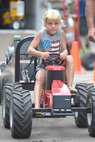 Chanielle Hayes of Stewartville moves the machine forward as she competes in the Kids Power Pedal Tractor Pull, hosted by Hammell Equipment, at Florence Park on the Fourth of July.