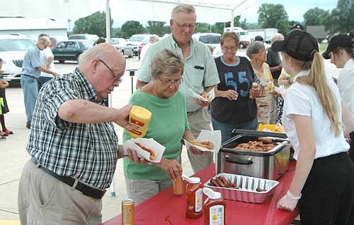 Lucien Cole of Stewartville, far left, puts mustard on his hot dog at the Fareway booth at the annual Dog Days of Summer Event last Thursday, Aug. 4. Cole is one of hundreds of people who attended the annual event, hosted by seven northeast Stewartville businesses.