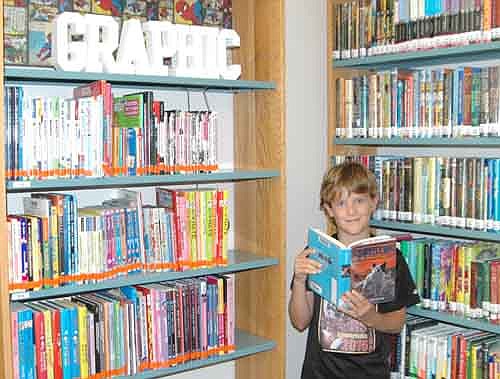 Nathan Jeche, 10, who will be a fifth grader at Bear Cave Intermediate School this September, stands near the newly expanded graphic books area at the Stewartville Public Library last week. "I love to read," Nathan said.