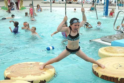 Alexis Diggins, 7, of Rochester, displays open-mouthed glee and struggles to grasp the ropes and maintain her balance as she crosses a set of imitation logs at the Stewartville pool on a warm and muggy Monday afternoon, Aug. 29.