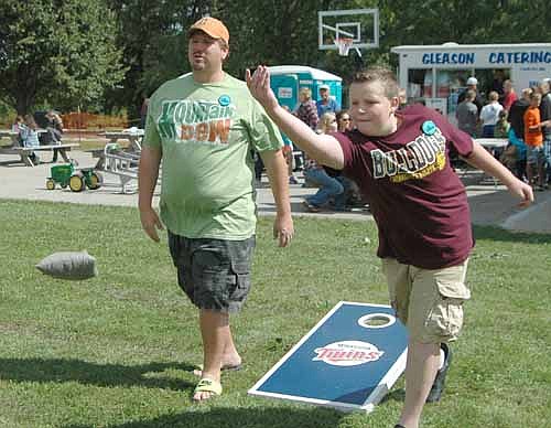 Nicholas Larsen, 15, of Rochester, shows good form as he releases the beanbag during a beanbag tournament at the 93rd annual High Forest Old Settlers Day on Saturday, Sept. 10. Mike Larsen, Nicholas's dad and playing partner, looks on at left.