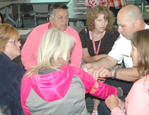 Vance Swisher, an EMT and the chief of the Stewartville Fire Department, right, displays the proper way to apply a tourniquet to a group of Stewartville School District paraprofessionals on Wednesday, Sept. 28