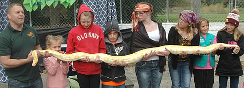 Jamie Pastika, director of the Reptile and Amphibian Discovery (RAD) Zoo of Owatonna, far left, helps seven children hold a python during a presentation at "Pets in the Park" on Saturday, Oct. 8.