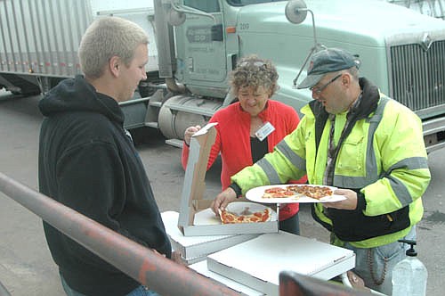 Nate Goeldi and Karen Goldsmith, members of Racine United Methodist Church, left, serve pizza to Todd Mangels of Rochester, a seasonal employee for All-American Co-op, on Saturday, Oct. 16.