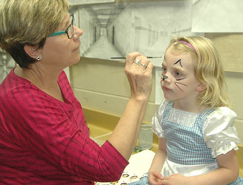 Nora Parker, 4, of Stewartville, holds her position as Rhona Baldner, an art teacher at Stewartville High School, applies cat whiskers at the SHS&#8200;Key Club's annual Halloween celebration on Saturday, Oct. 29. The Key Club's annual event includes face painting, games, a visit to a darkened, spooky room, craft making, Halloween treats and more.