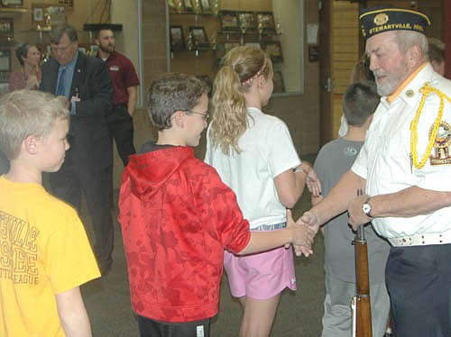 Ben Hagen, a sixth grader, above, shakes hands with veteran Roy Fritz at the annual Veterans Day ceremony at Stewartville High School-Middle School on Monday, Nov. 14. Chase Neubauer, a seventh grader, waits in line at far left.
