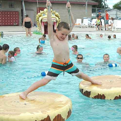 Tommy Lofgren, 7, of Stewartville, grasps the ropes tightly as he struggles to cross the imitation logs at the Stewartville pool on Tuesday afternoon, June 28.